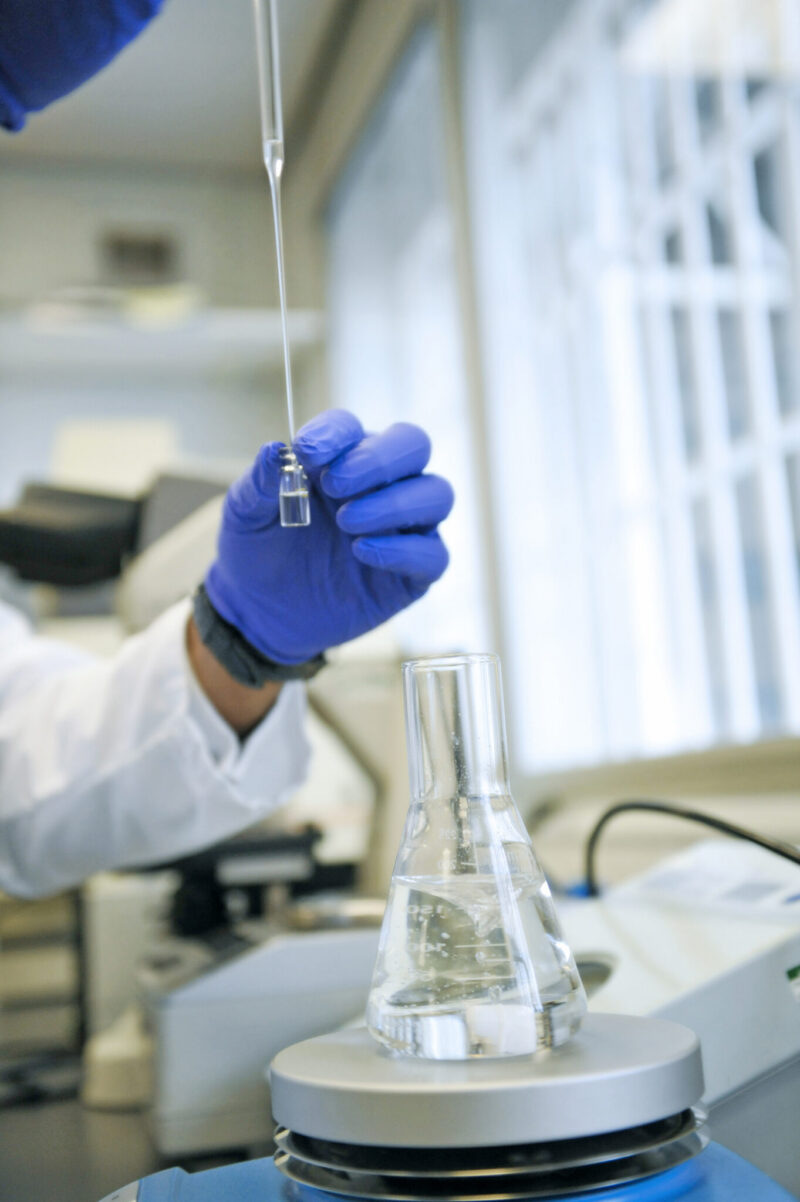 _ACA2991 Researcher's hand holding a test tube in a lab.